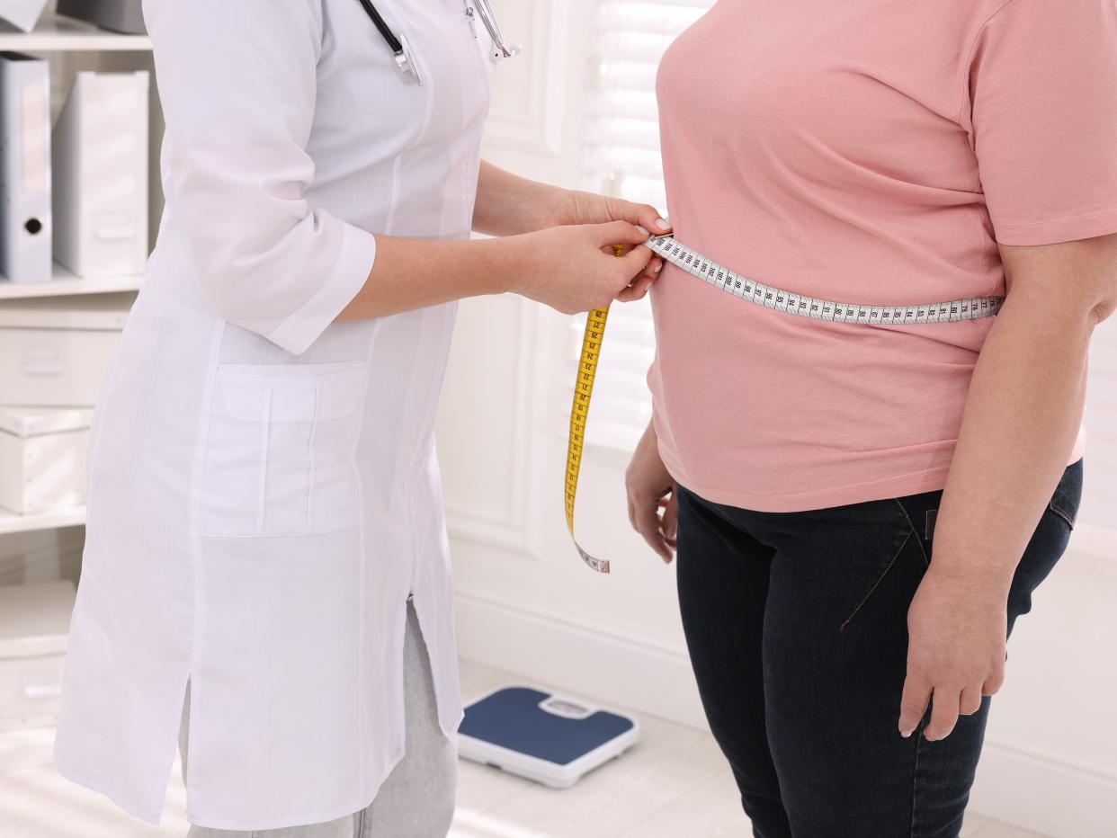 Doctor measures a woman's waist with a tape measure