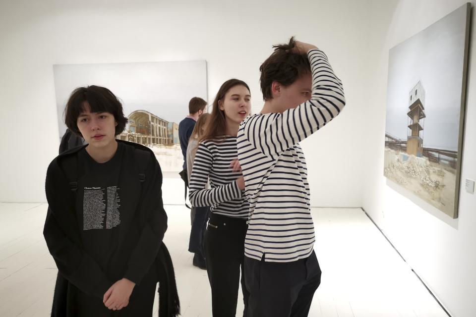 In this photo taken on Sunday, Feb. 17, 2019, visitors attend an exhibition by Russian artist Pavel Otdelnov, in Moscow, Russia . Pavel Otdelnov, a Russian artist who grew up in Dzerzhinsk, the center of the nation's chemical industries 355 kilometers (220 miles) east of Moscow, focused on the city, one of the most polluted in Russia, in his new 'Promzona' art show. (AP Photo/Ivan Kochkarev)