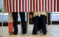 A child looks out from a voting booth as French citizens living in the United States cast their ballots for the French presidential run-off between Emmanuel Macron and Marine Le Pen, at the French Embassy in Washington, U.S., May 6, 2017. REUTERS/Mike Theiler