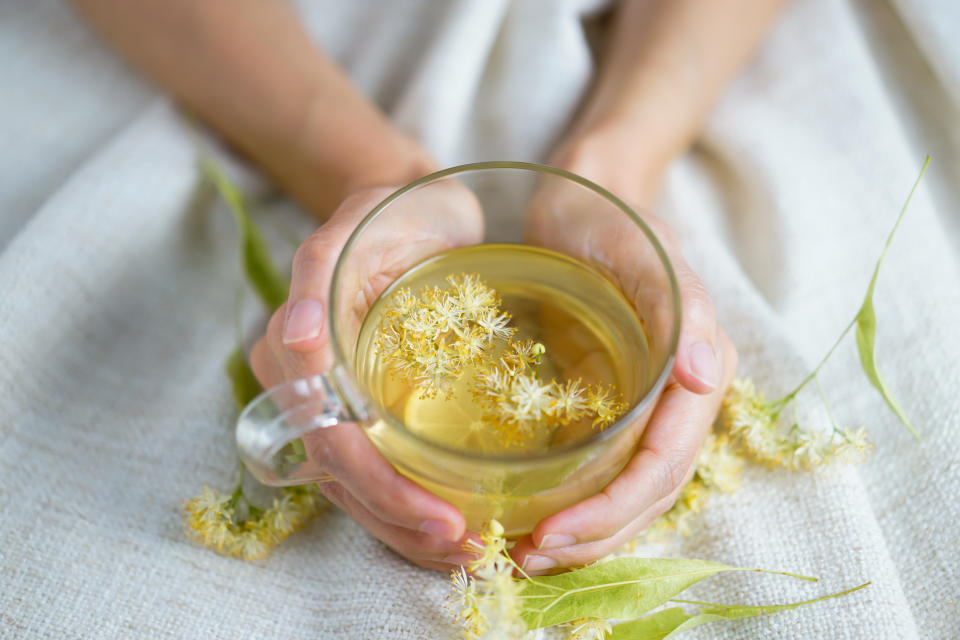 Hands hold a glass cup of herbal tea. Source: Getty Images