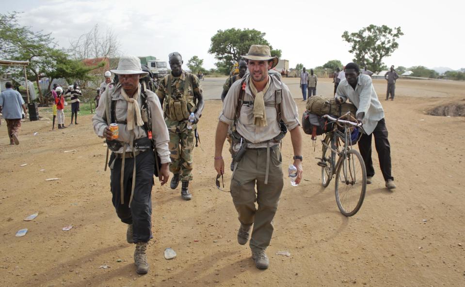 In this photo taken Wednesday, April 9, 2014, former British Army captain Levison Wood, center, sets out walking along the Nile river from Juba, in South Sudan. Close calls with crocodiles and a brutal civil war have not deterred Levison from attempting to walk the length of the Nile, a 4,250 mile journey along the world's longest river that will see him pass through seven countries. (AP Photo/Ilya Gridneff)