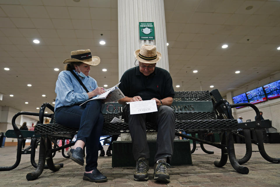 A couple looks over a racing program before the 147th running of the Kentucky Derby at Churchill Downs, Saturday, May 1, 2021, in Louisville, Ky. (AP Photo/Brynn Anderson)