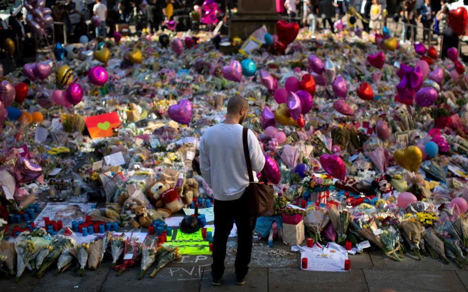 A man stands next to flowers for the victims of Monday's bombing at St Ann's Square in central Manchester - Credit: AP