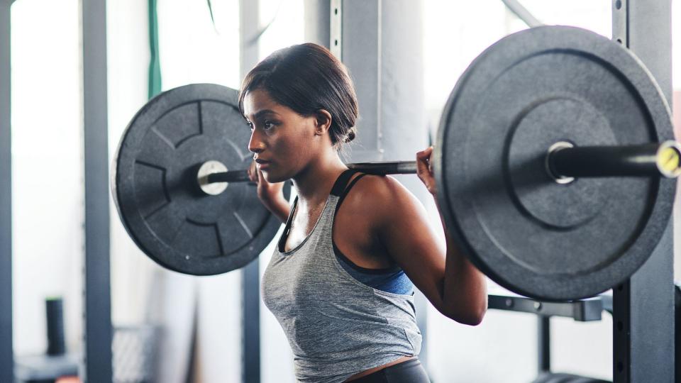 Woman holding barbell on shoulders ready for squat