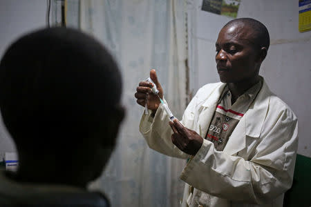 A nurse (R), prepares to give an injection to Voyage, 40, a Pygmy man who is suffering from a wound on his finger that has turned gangrenous, at the health centre in the village of Bugarula on Idjwi island in the Democratic Republic of Congo, November 24, 2016. REUTERS/Therese Di Campo