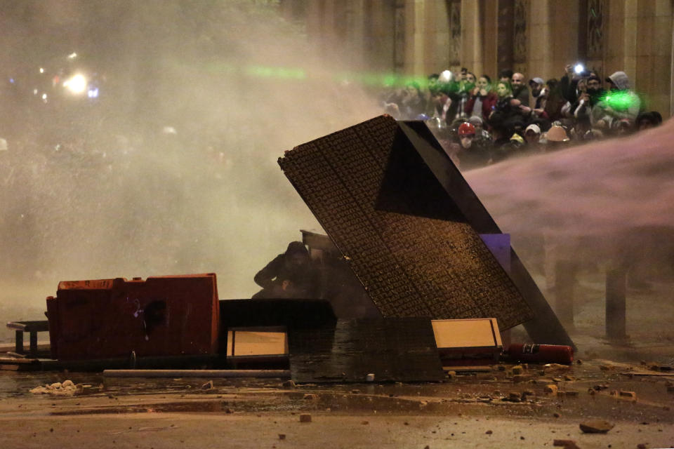 Anti-government protesters are sprayed by a water canon, during ongoing protests against the political elites who have ruled the country for decades, in Beirut, Lebanon, Sunday, Jan. 19, 2020. Lebanese security forces used tear gas, water cannons and rubber bullets in clashes with hundreds of anti-government protesters outside the country's Parliament on Sunday, as violence continued to escalate in a week of rioting in the capital. (AP Photo/Hassan Ammar)