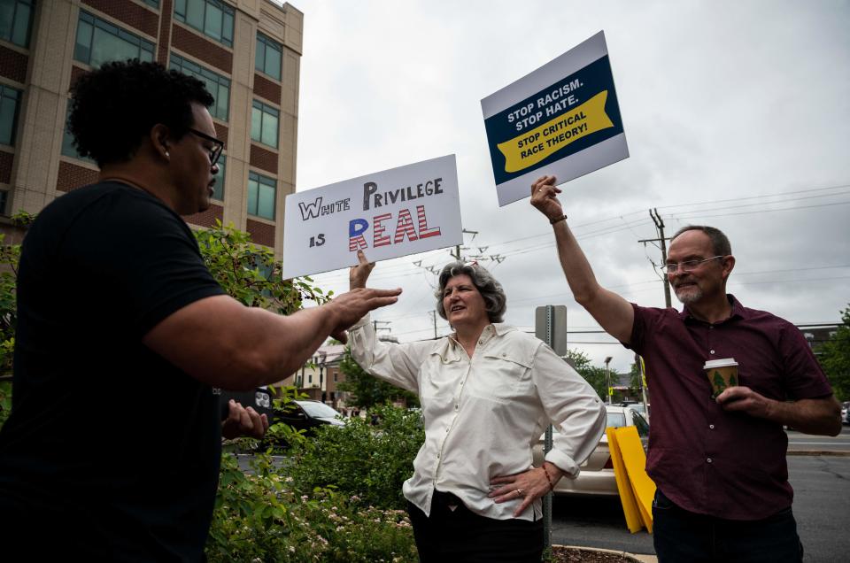 Two men (L and R) against "critical race theory" (CRT) being taught in schools speak with a counterprotester during a rally at the Loudoun County Government center in Leesburg, Va., on June 12, 2021.