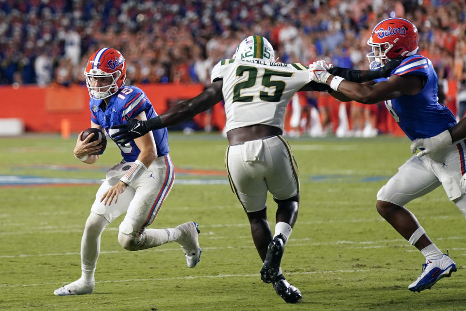 Florida quarterback Graham Mertz, left, scrambles for yardage past Charlotte linebacker Prince Bemah (25) during the first half of an NCAA college football game, Saturday, Sept. 23, 2023, in Gainesville, Fla. (AP Photo/John Raoux)