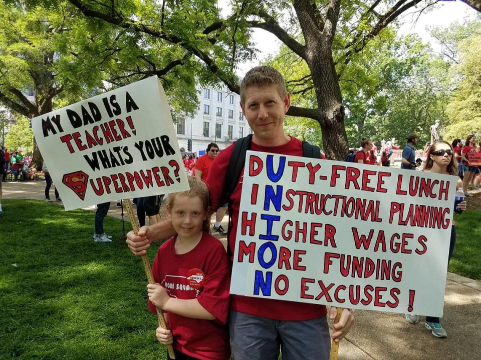 Frank Burns, a math teacher at Moore Square Middle School, with his daughter, Madeline, a first-grader at Willow Springs Elementary. Thousands of teachers carried signs May 1, 2019, in downtown Raleigh during the May 1 “Day of Action” organized by the N.C. Association of Educators. The signs ranged from clever pop culture references to more direct demands for higher pay, supplies and respect. Jessica Banov/jbanov@newsobserver.com