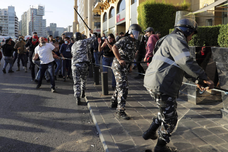 Riot police swing batons at anti-government protesters who try to remove barbed wire blocking a road to the parliament building during a protest in downtown Beirut, Lebanon, Tuesday, Nov. 19, 2019. Scuffles have broken out in central Beirut as hundreds of anti-government protesters tried to prevent lawmakers from reaching Parliament. (AP Photo/Hassan Ammar)