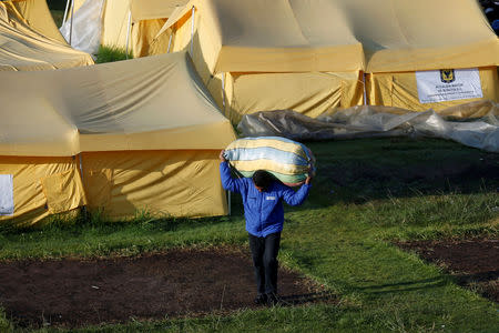 A Venezuelan migrant carries his belongings out of a tent inside a temporary humanitarian camp that is closed by the government, in Bogota, Colombia January 15, 2019. REUTERS/Luisa Gonzalez