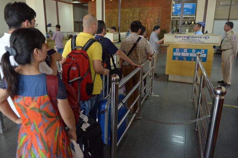 Chinese tourists (R) queue at the immigration check point after arriving in Cambodia on May 16, 2014