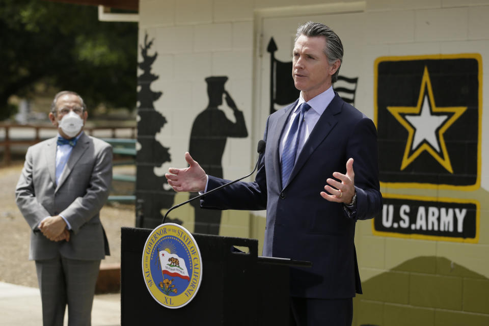 FILE - California Gov. Gavin Newsom speaks during a news conference as CalVet Secretary Vito Imbasciani looks on at the Veterans Home of California, Friday, May 22, 2020, in Yountville, Calif. California's governor has signed a law he says will help military service members who were discharged under "don't ask, don't tell" policies to reestablish eligibility for Veterans Affairs benefits. Newsom said Saturday, Sept. 17, 2022, many veterans who were discharged because of sexual or gender identities don't know how to access benefits they might be eligible for. The law requires the state to create a grant program to help LGBTQ veterans through the process. (AP Photo/Eric Risberg, Pool, File)