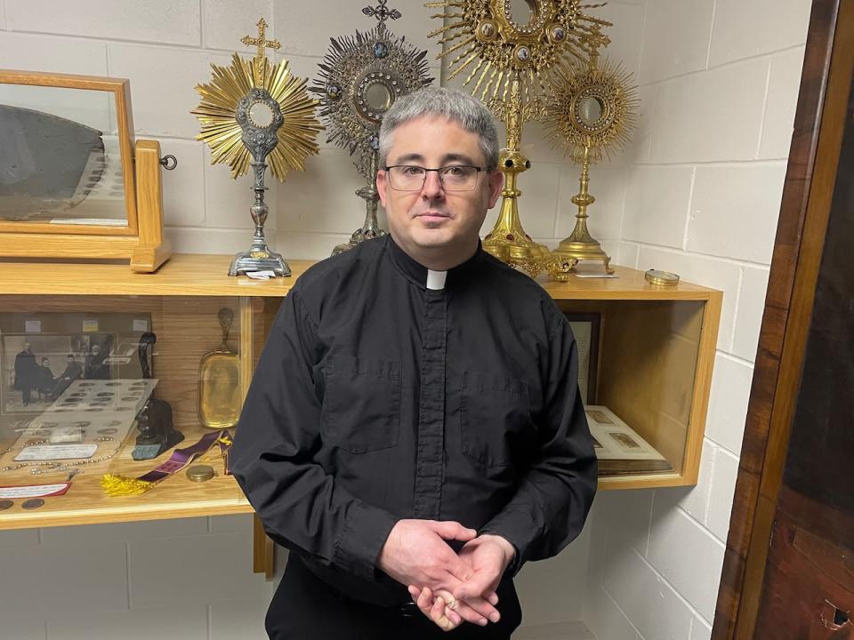 Father Chris Sherren, chancellor of the diocese of Charlottetown, stands in front of one of display cases holding a wide vareity of artifacts. 