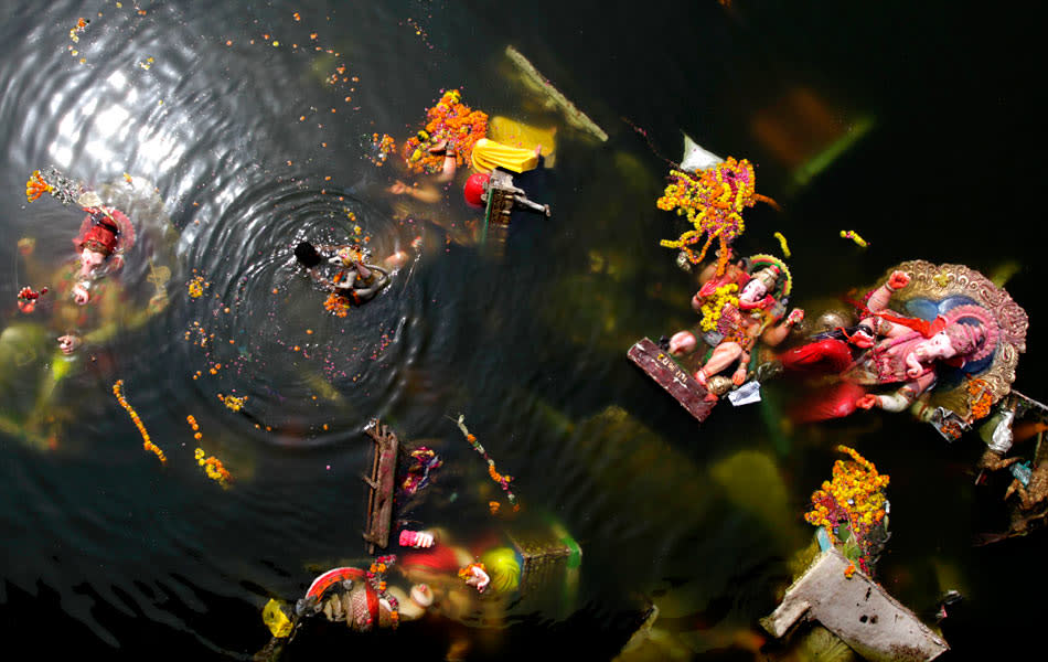 A man searches for reusable items amid immersed idols of the elephant-headed Hindu God Ganesh in the Sabarmati River. Action groups in Mumbai insist that there is a silver lining amid all of this: In 2009, 8,383 household idols were immersed in artificial ponds. In 2010, they maintain, the number grew to 13,866.