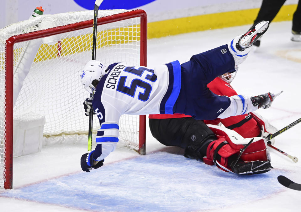 Winnipeg Jets' Mark Scheifele (55) trips over Ottawa Senators goalie Matt Murray (30) during the third period of an NHL hockey game Wednesday, April 14, 2021, in Ottawa, Ontario. (Sean Kilpatrick/The Canadian Press via AP)