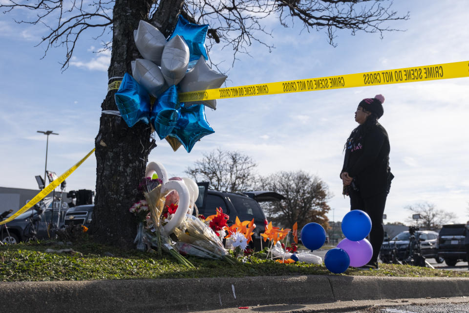 Mary Chatkovsky places balloons and flowers on a memorial outside of the Chesapeake, Va., Walmart on Thursday, Nov. 24, 2022. Andre Bing, a Walmart manager, opened fire on fellow employees in the break room of the Virginia store, killing six people in the country’s second high-profile mass shooting in four days, police and witnesses said Wednesday. (Billy Schuerman/The Virginian-Pilot via AP)