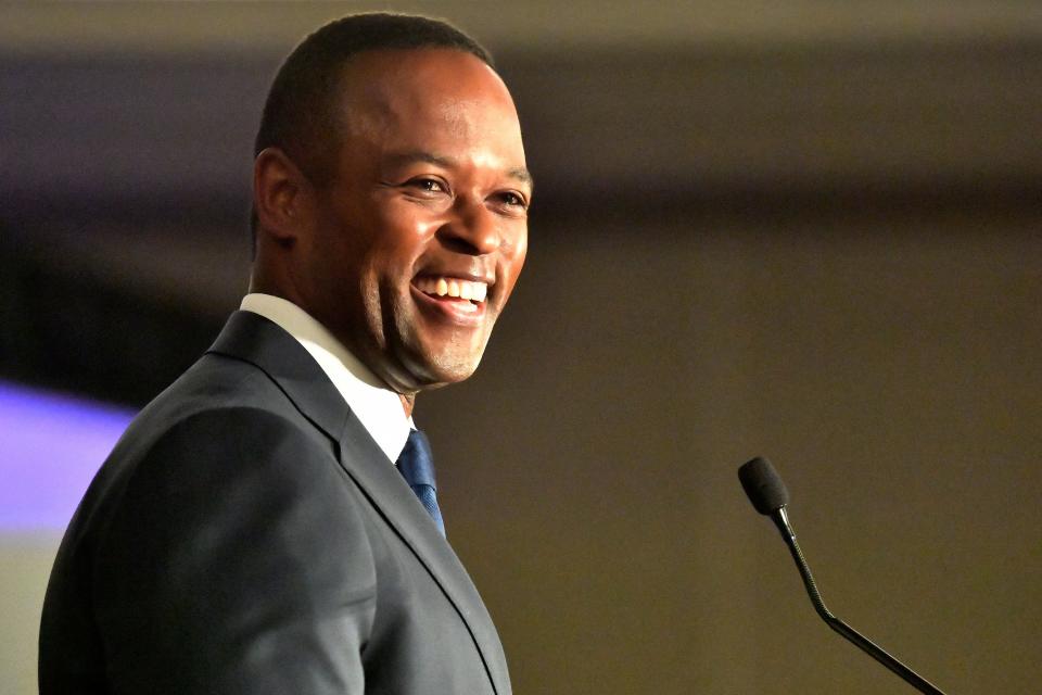 man in suit smiles at microphone