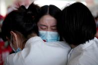 Medical workers hug at the Wuhan Tianhe International Airport