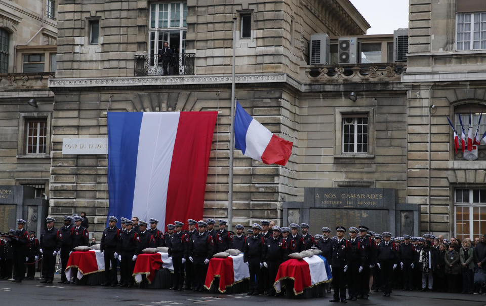 Police officers stand at attention by the coffins of the four victims of last week's knife attack during a ceremony in the courtyard of the Paris police headquarters Tuesday, Oct. 8, 2019 in Paris. France's presidency says the four victims of last week's knife attack at the Paris police headquarters will be posthumously given France's highest award, the Legion of Honor. (AP Photo/Francois Mori)