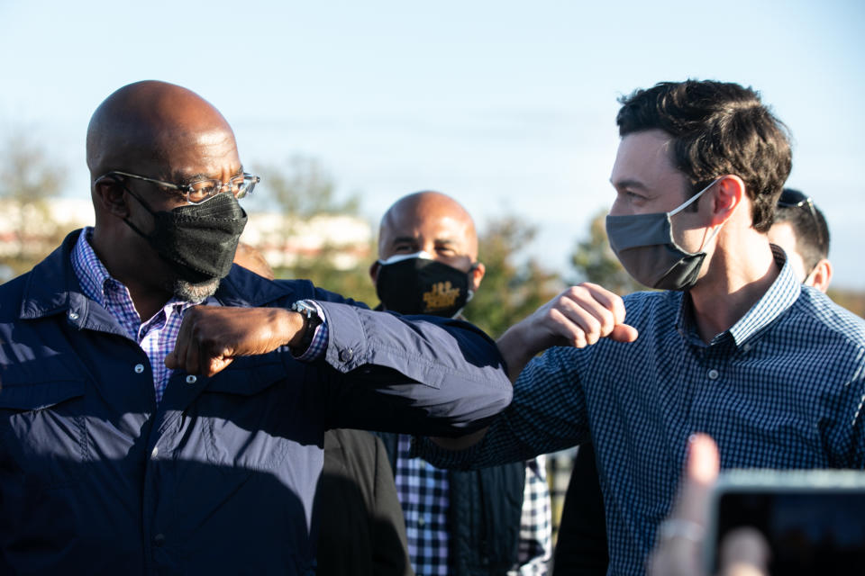 Georgia Democratic U.S. Senate candidates Jon Ossoff (R) and Raphael Warnock (L) taps elbows during a rally for supporters on November 15, 2020 in Marietta, Georgia. (Photo by Jessica McGowan/Getty Images)                                  