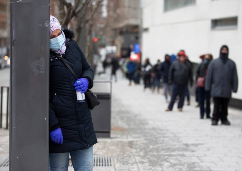 A woman leans on a pole wile she waits beside the line up as the city's public health unit holds a walk-in clinic testing for coronavirus disease (COVID-19) in Montreal