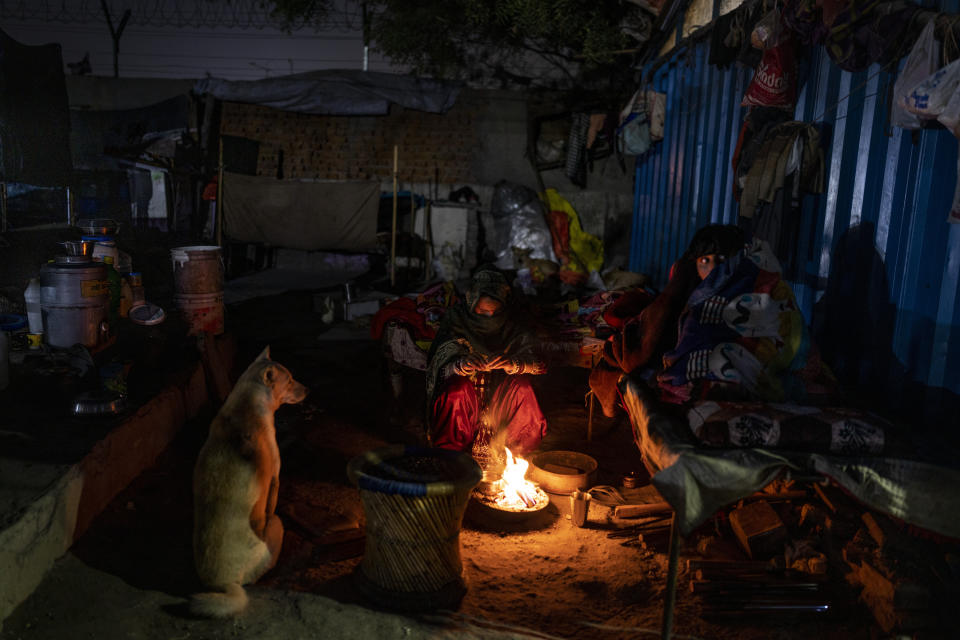 A homeless family and their dog sit around a bonfire outside a night shelter for homeless people on a cold night in New Delhi, Wednesday, Dec. 28, 2022. Official figures show the city’s 195 homeless shelters can accommodate only about 19,000 people, leaving tens of thousands struggling to keep warm. (AP Photo/Altaf Qadri)