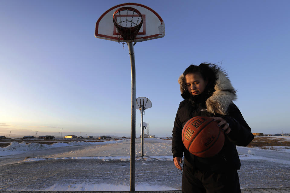 In this Feb. 17, 2019, photo, Deidre Levi carries her basketball as she walks to work in the Native Village of St. Michael, Alaska. Levi says she spoke up about being sexually assaulted because she wanted to be a role model for girls in Alaska. (AP Photo/Wong Maye-E)