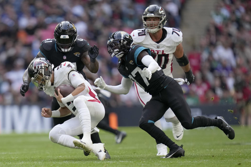 Atlanta Falcons quarterback Desmond Ridder (9), left, is sacked by Jacksonville Jaguars linebacker Josh Allen (41) and Jacksonville Jaguars tight end Evan Engram (17), right, during the first quarter of an NFL football game between the Atlanta Falcons and the Jacksonville Jaguars at Wembley stadium in London, Sunday, Oct. 1, 2023. (AP Photo/Kirsty Wigglesworth)