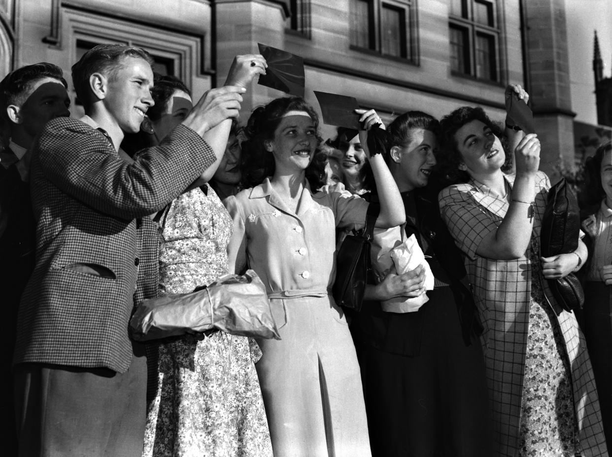 1948: People look at an eclipse through cardboard in Sydney, Australia.  