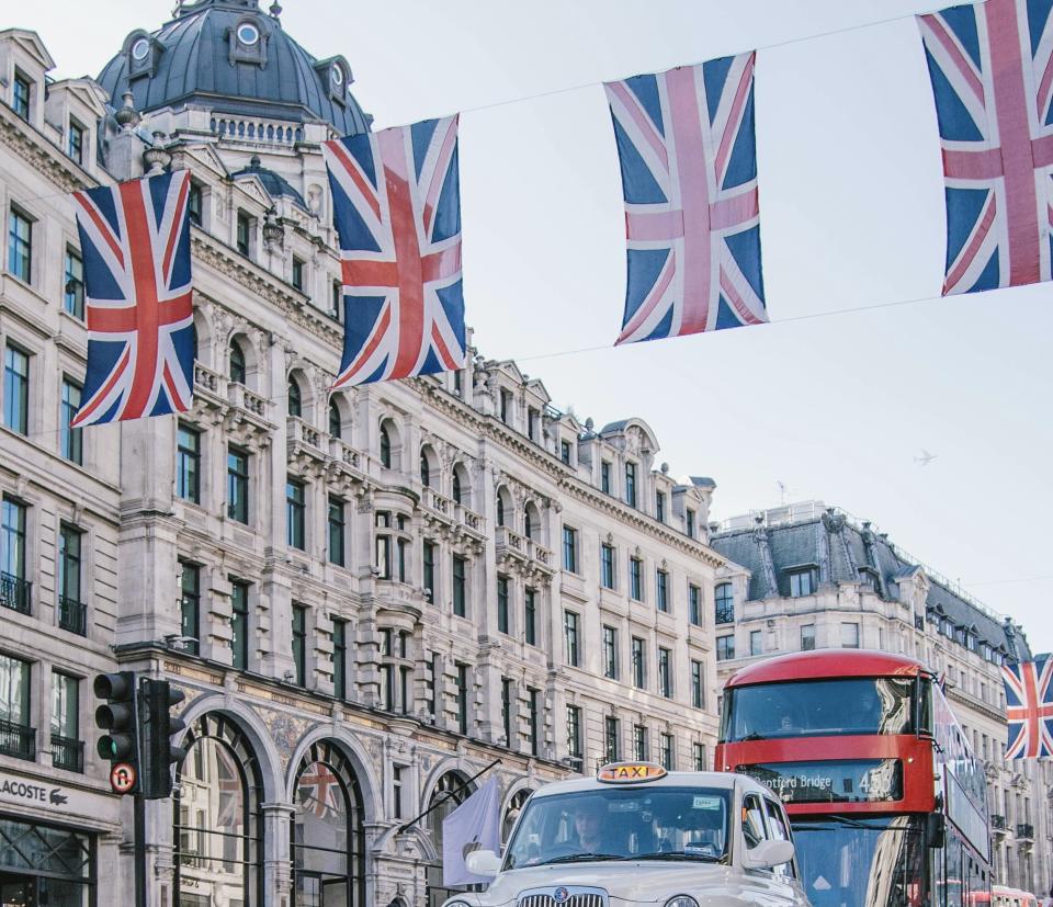 London is a bustling city of Europe that is well known as one of the most popular cities to visit.
Pictured: a street of London with flags decorating the buildings and historic building in the background 