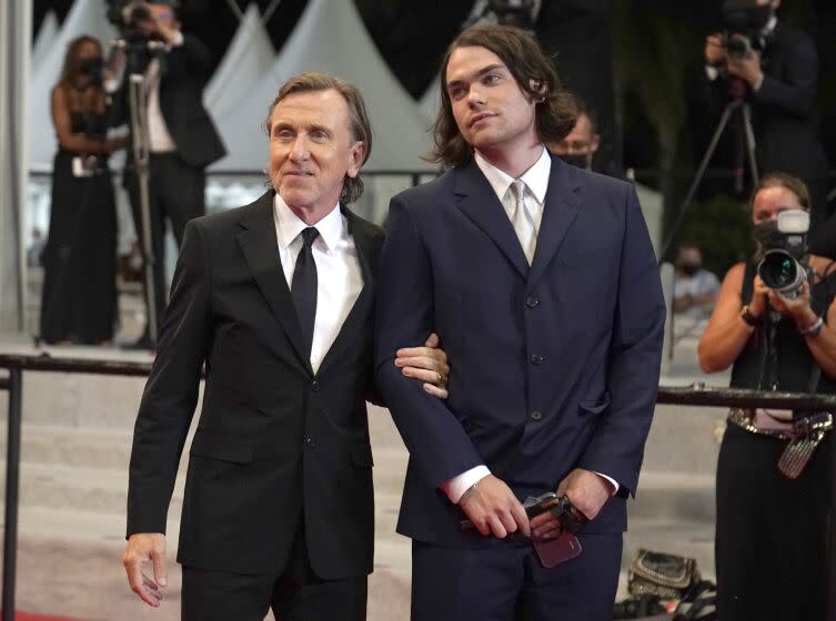 A father and son wearig suits as they pose for cameras at a movie premiere