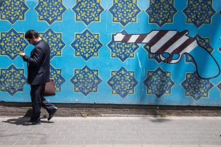 A man walks in front of an anti-U.S. mural in Tehran