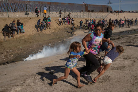FILE PHOTO: Maria Meza, a 40-year-old migrant woman from Honduras, part of a caravan of thousands from Central America trying to reach the United States, runs away from tear gas with her five-year-old twin daughters Saira Mejia Meza (L) and Cheili Mejia Meza (R) in front of the border wall between the U.S and Mexico, in Tijuana, Mexico November 25, 2018. REUTERS/Kim Kyung-hoon/File Photo
