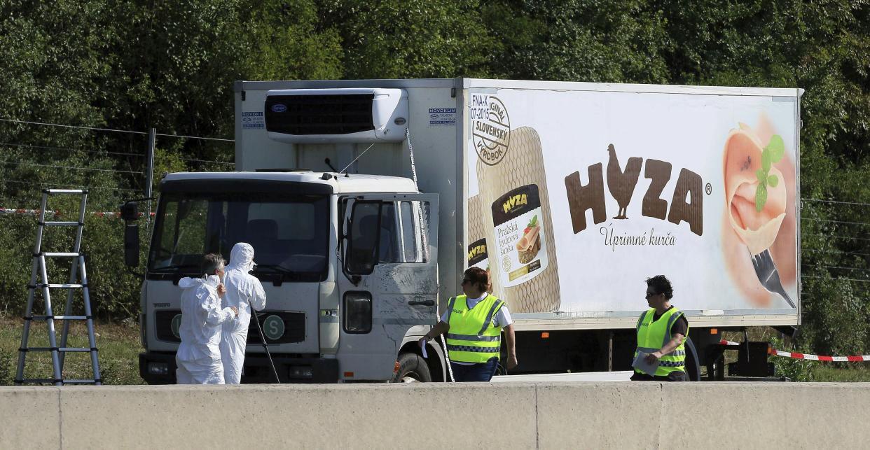 In this Thursday, Aug. 27, 2015 file photo, investigators stand near an abandoned truck on the shoulder of Highway A4 near Parndorf, Austria, south of Vienna. A Hungarian court has extended the prison sentences of four human traffickers convicted last year for their roles in a 2015 in which 71 migrants suffocated to death in the back of a refrigerated truck found on a highway in Austria.