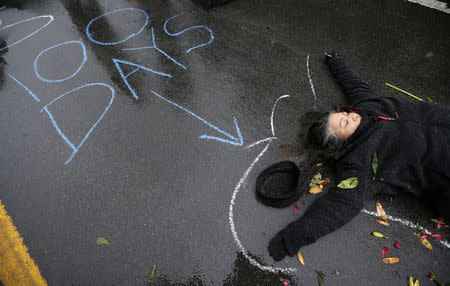 A demonstrator lays on the ground with a chalk outline representing a mock crime scene during a protest marking the 100th day since the shooting death of Michael Brown in St. Louis, Missouri November 16, 2014. REUTERS/Jim Young