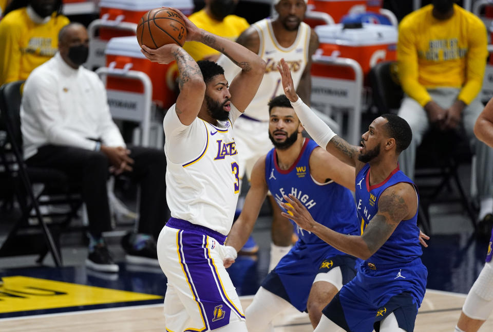 Los Angeles Lakers forward Anthony Davis, left, looks to pass the ball as Denver Nuggets guards Jamal Murray, center, and Monte Morris defend during the first half of an NBA basketball game Sunday, Feb. 14, 2021, in Denver. (AP Photo/David Zalubowski)