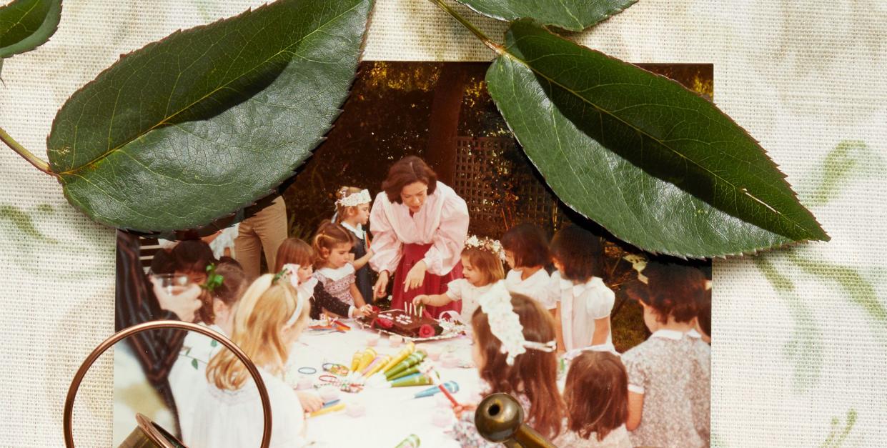 a collage of leaves, miniature watering cans in brass, chrome, and copper, a photo of a woman standing over a birthday cake with young girls wearing flower crowns, all placed on a piece of floral fabric