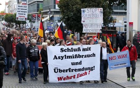 Supporters of the far-right National Democratic Party (NPD) hold banners and German flags during a march in Riesa, Germany, September 9, 2015. The main banner (C) reads "Stop the asylum abuse and excessive foreign infiltration. Defend yourselves!" REUTERS/Fabrizio Bensch