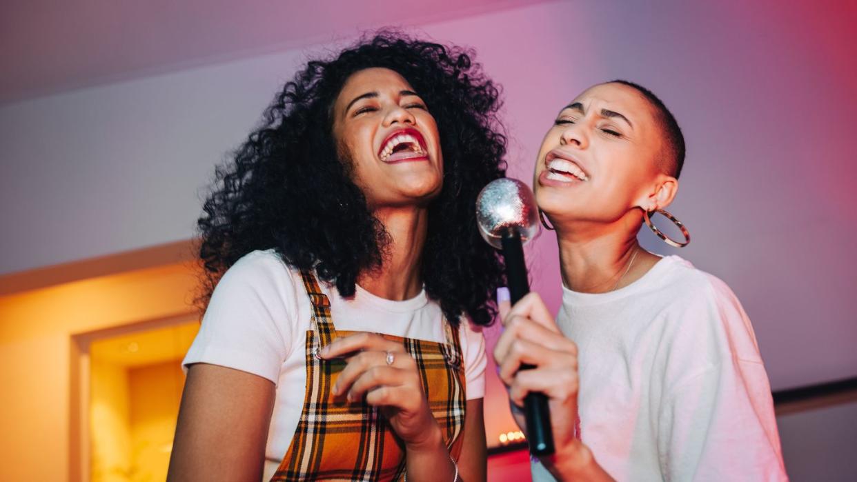 best friends singing into a microphone on karaoke night