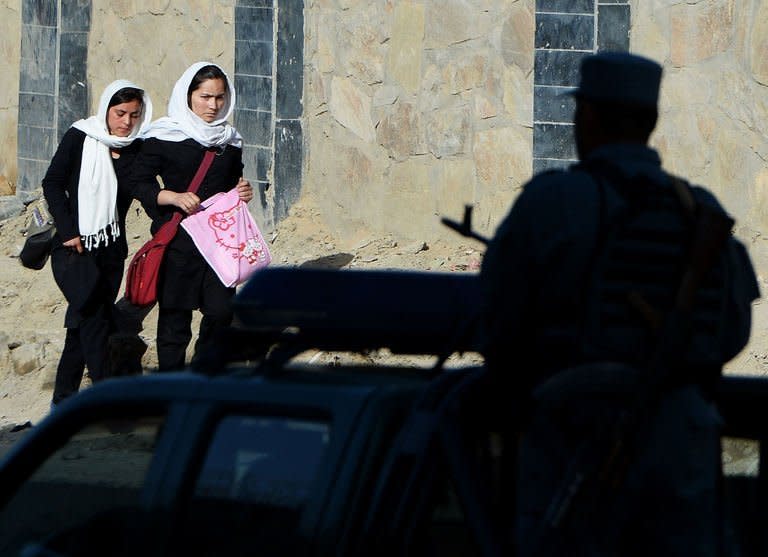 An Afghan policeman (R) keeps watch as schoolgirls walk near the entrance of the presidential palace in Kabul on June 25, 2013. Taliban gunmen and bombers using fake NATO identification attacked an entrance to the Afghan presidential palace in the heart of Kabul on Tuesday, just a week after insurgent leaders opened an office in Qatar for peace talks