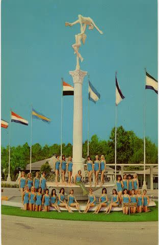<p>Courtesy of Florida State Parks</p> A postcard of the Weeki Wachee Mermaids in 1966 in front of the statue