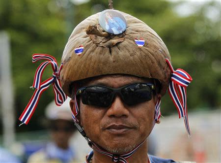 An anti-government protester wears a hat made of a coconut husk with a badge featuring a picture of Thailand's King Bhumibol Adulyadej during a rally outside the Government House in Bangkok May 17, 2014. REUTERS/Chaiwat Subprasom