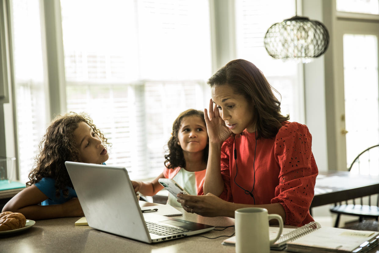 Mother working from home with children in background (Getty Images)