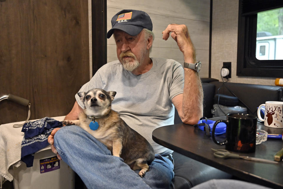 Bernard Carr, and his pet chihuahua Wiley pass the time in a travel trailer at Henry Wiley State Park in Prestonsburg, Ky., Tuesday, Sept. 6, 2022. The 64-year-old Marine Corps veteran spends most of his time outdoors listening to music on the one radio station he can receive at the park. (AP Photo/Timothy D. Easley)