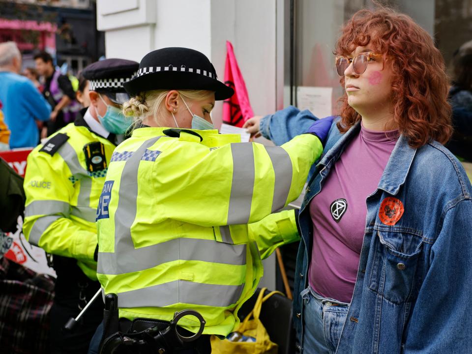 A climate activist from XR is searched by police officers before being arrested (AFP via Getty Images)