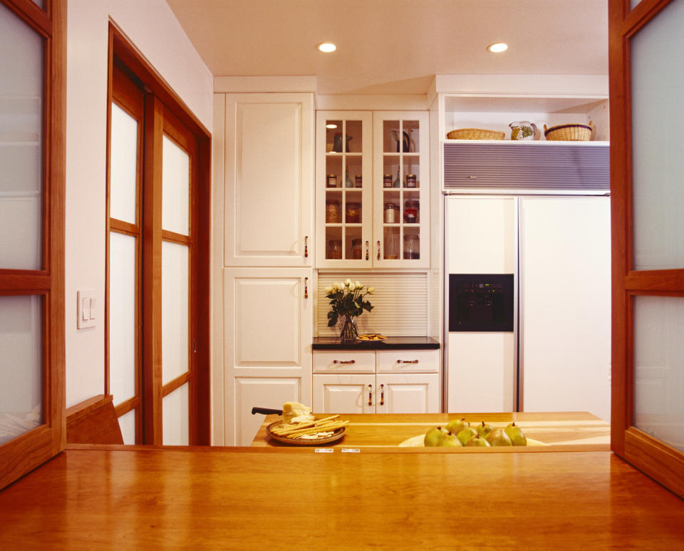 An immaculate kitchen with some pears and cheese on a cutting board