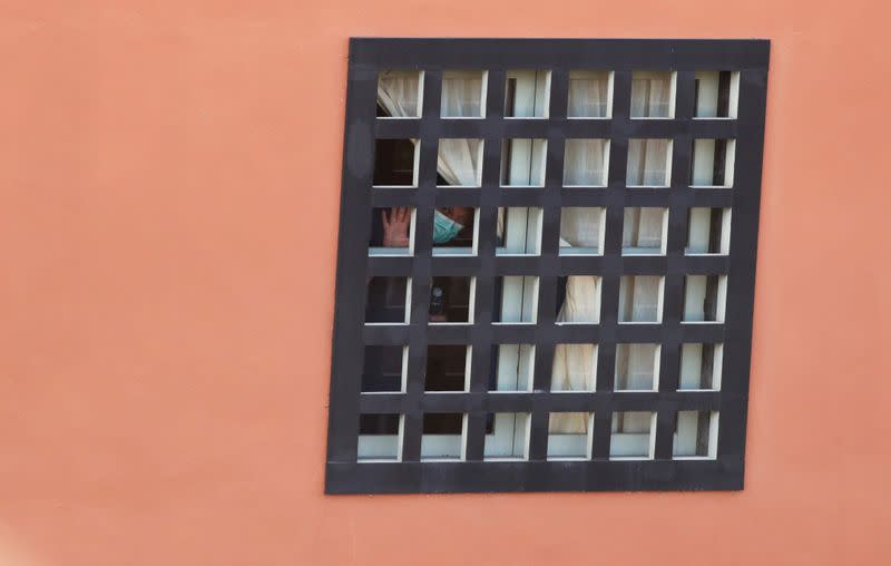 A tourist looks through the hotel window H10 Costa Adeje Palace, which is on lockdown after novel coronavirus has been confirmed in Adeje