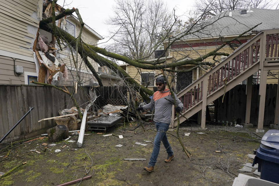 Eric Rose picks up debris from a tree that crashed through his neighbor's house and landed in his backyard during a storm in Sacramento, Calif., Wednesday, Jan. 27 2021. High-winds and rain pelted the region causing damage throughout the area. (AP Photo/Rich Pedroncelli)