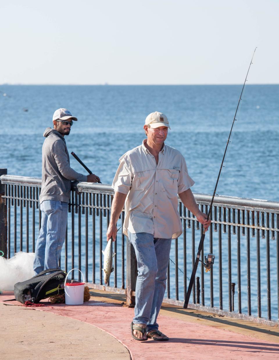 Jerry Lenox, of Pensacola, right, carries a fish back to his vehicle at the recently reopened Palafox Pier in downtown Pensacola on Wednesday, Nov. 2, 2022.